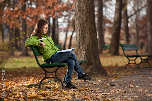 Girl reading book sitting in park