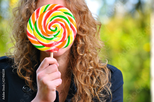woman is hiding behind a huge lollipop