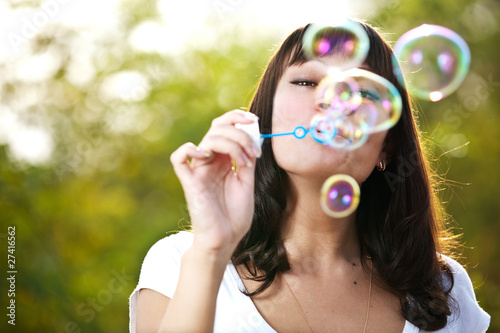 Young beautiful girl blowing bubbles outdoors