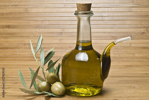 Aceitera con aceite de oliva y aceitunas verdes.