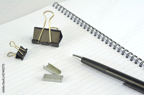 Empty spiral notebook with paper clip, pencil and pen