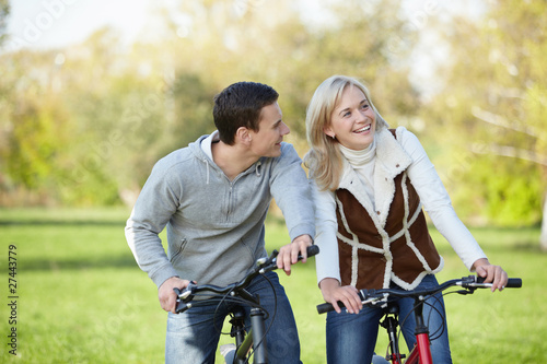 Young happy couple in the park on bicycles