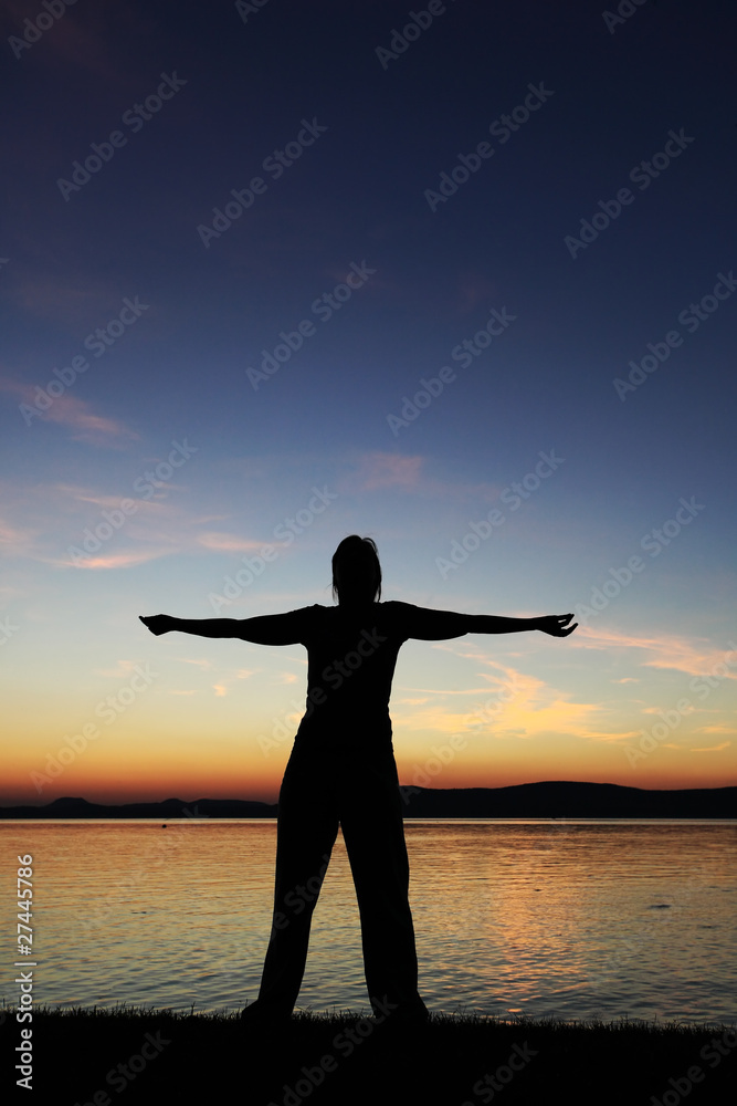 Young woman with raised hands standing at coast