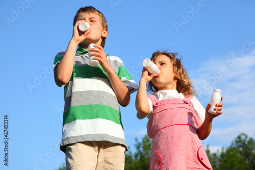 boy and girl against sky, with pleasure drink yoghurt