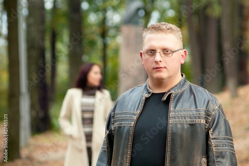 Man in autumn park with girlfriend in background