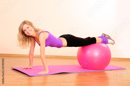 Young beautiful fitness girl with pink ball exercising in the gy