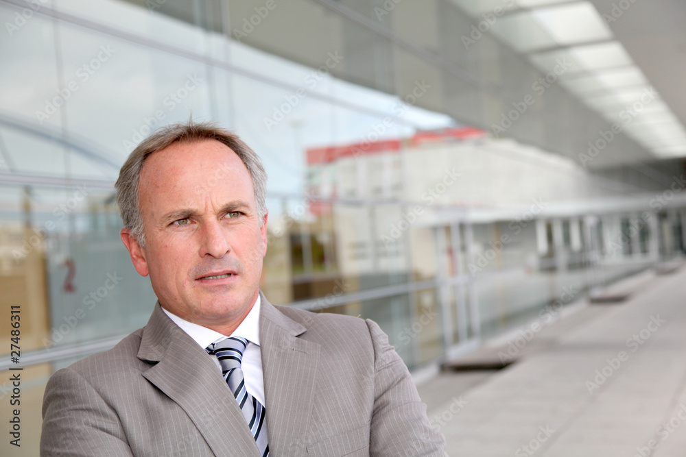 Businessman standing outside modern building Businessman standing outside modern building