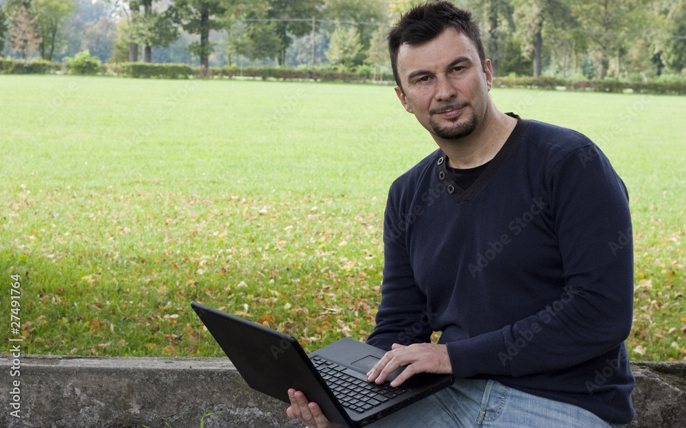 Young Adult Working in the Park with Laptop Computer Young Adult Working in the Park with Laptop Computer