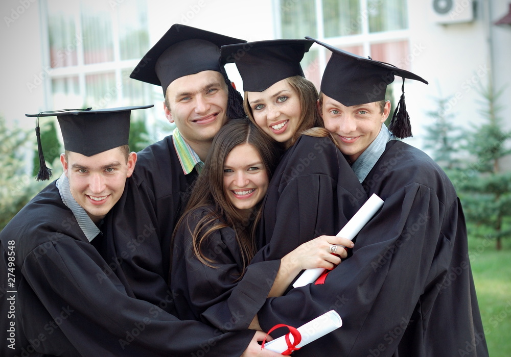 Graduates embrace, enjoy and look at the camera Graduates embrace, enjoy and look at the camera