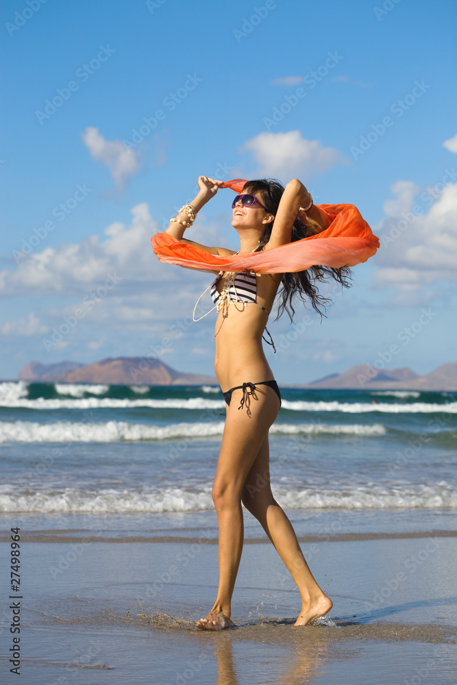 Naklejka premium young woman dancing with kerchief against the blue sky