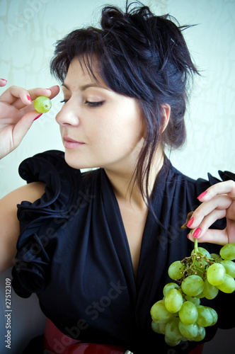 Young girl with grape and closed eyes