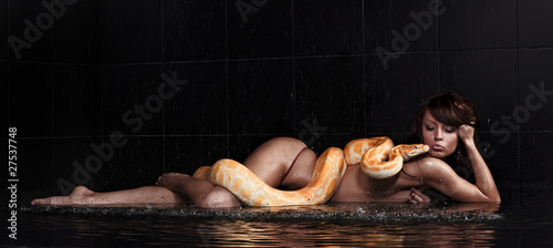 Beautiful woman lying with Python in water