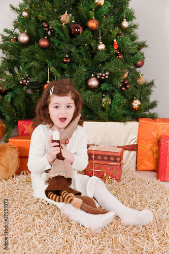 Wondering little girl in a front of Christmas-tree