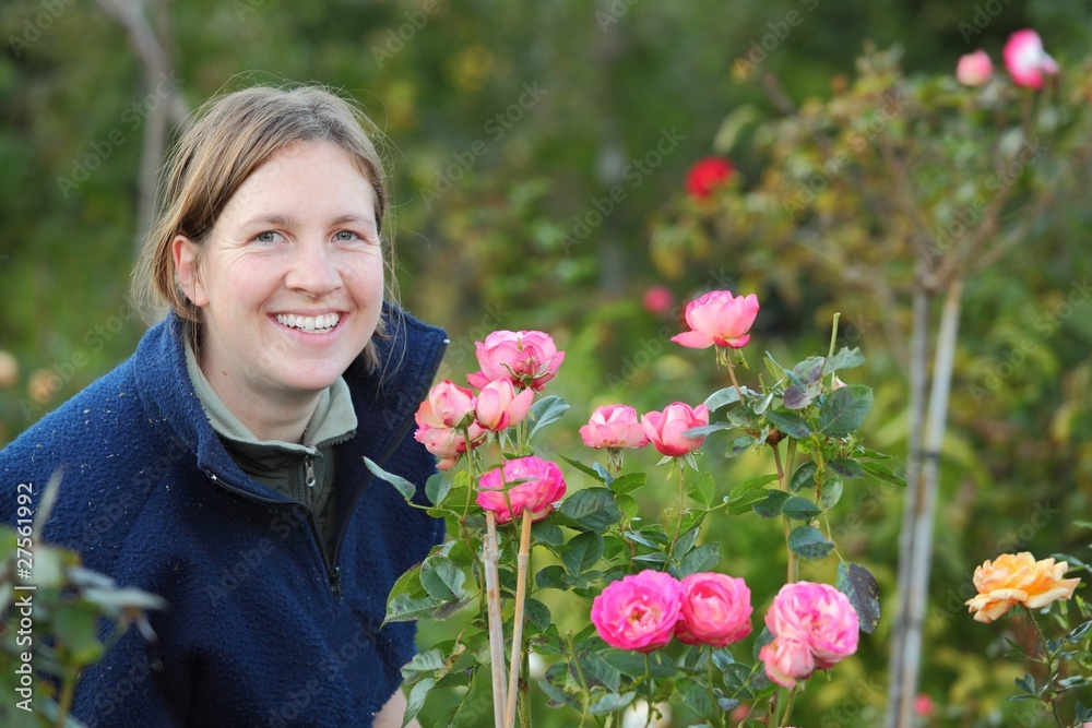 Frau erfreut sich an ihren Rosen im Garten