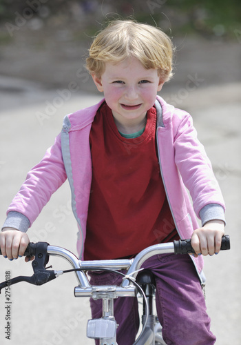 cute little girl driving bicyle at sunny day