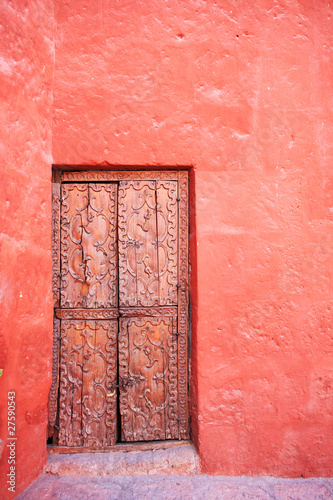 Red wall with old decorative stone door.