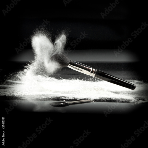 a composition with a powder brush and white loose powder