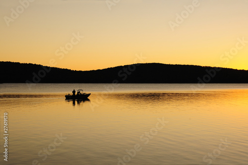 Early morning fishing boat on a lake at dawn