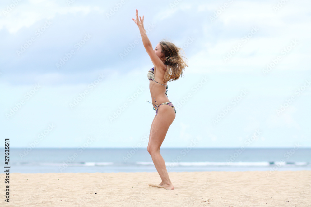 Young woman standing on a beach and enjoying the sun Young woman standing on a beach and enjoying the sun