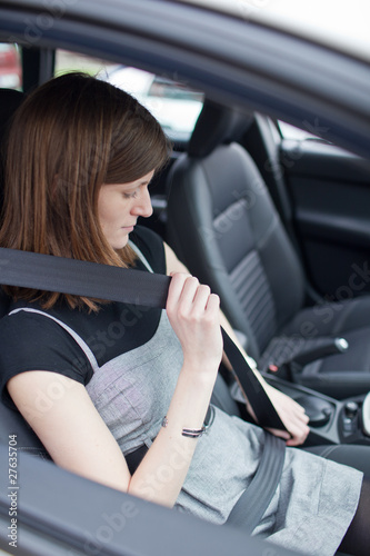 Road safety concept - Pretty young woman fastening her seat belt