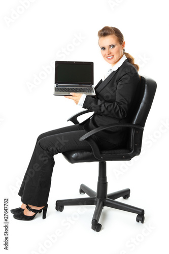Smiling business woman holding laptop in hand with blank screen
