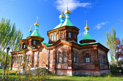 The Russian Orthodox Holy Trinity Cathedral in Karakol, Church,  stands adorned with golden domes and crosses, its wooden frame contrasted the clear blue winter sky photo
