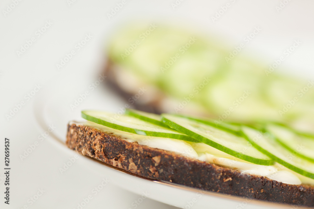 pieces of rye bread with sliced cucumbers and cheese on plate pieces of rye bread with sliced cucumbers and cheese on plate