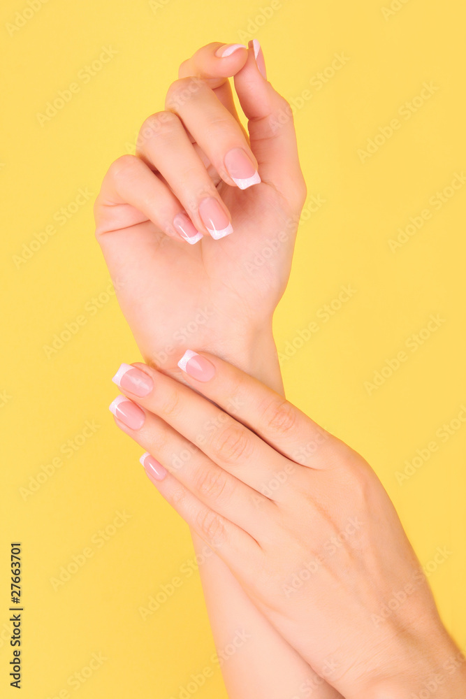 Beautiful woman hands with french manicure on yellow background Beautiful woman hands with french manicure on yellow background