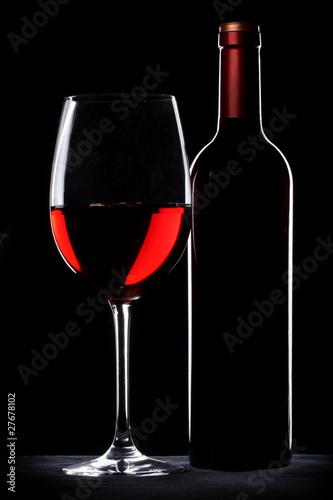 Red wine bottle and glass silhouette over black background