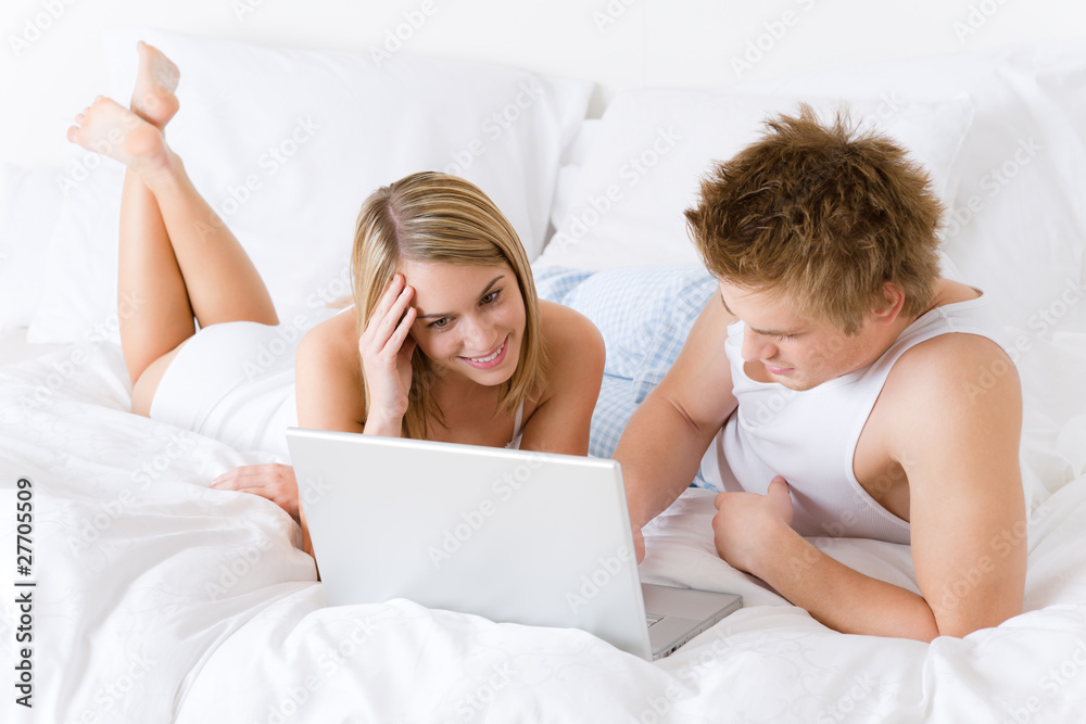 Young couple relax in bed with laptop Young couple relax in bed with laptop