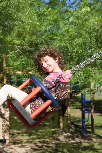 girl swinging on swing happy in trees outdoor © lunamarina