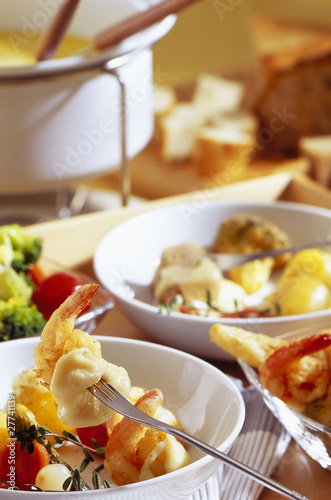 Rich fondue with sea food and fondue set in the background.