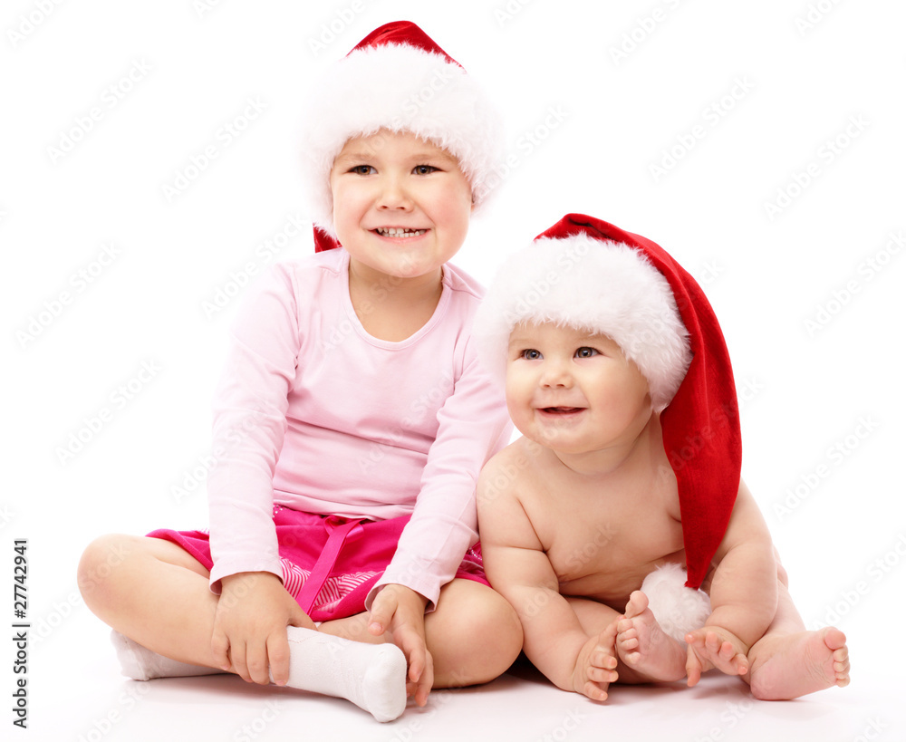 Two children wearing red Christmas caps and smile Two children wearing red Christmas caps and smile
