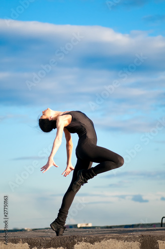 dancing woman over blue sky. Yoga