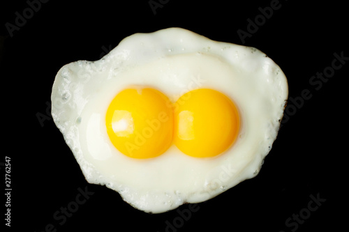 Fried two-yolks egg on black background