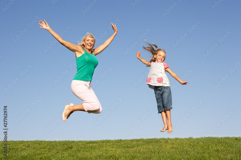 Senior woman with granddaughter jumping in air Senior woman with granddaughter jumping in air