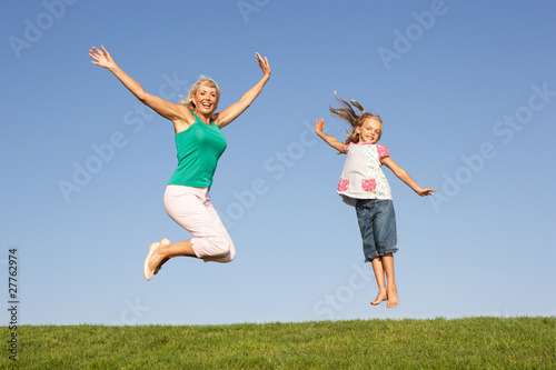 Senior woman with granddaughter jumping in air