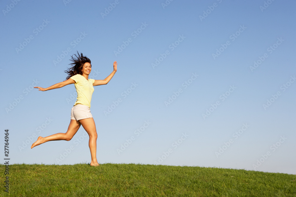 Young woman running through field