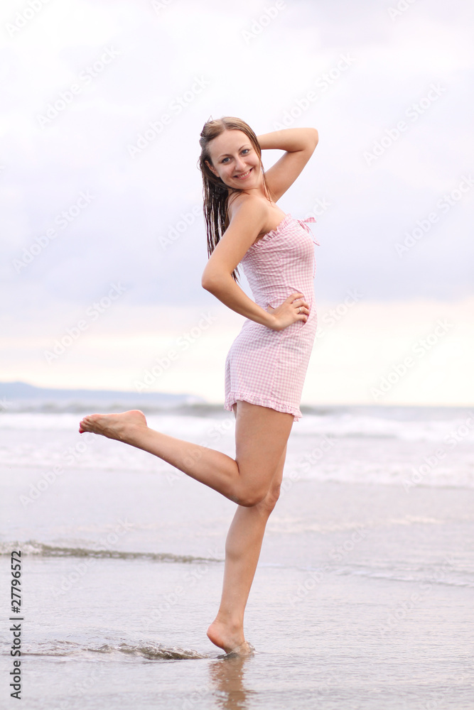 Young woman standing on a beach and enjoying the sun Young woman standing on a beach and enjoying the sun