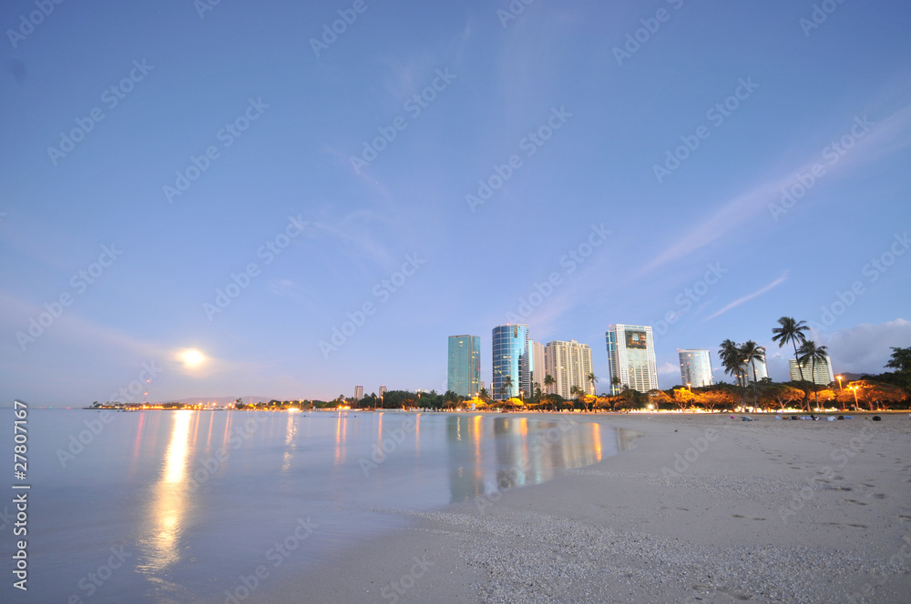 Moon set over the ocean with buildings