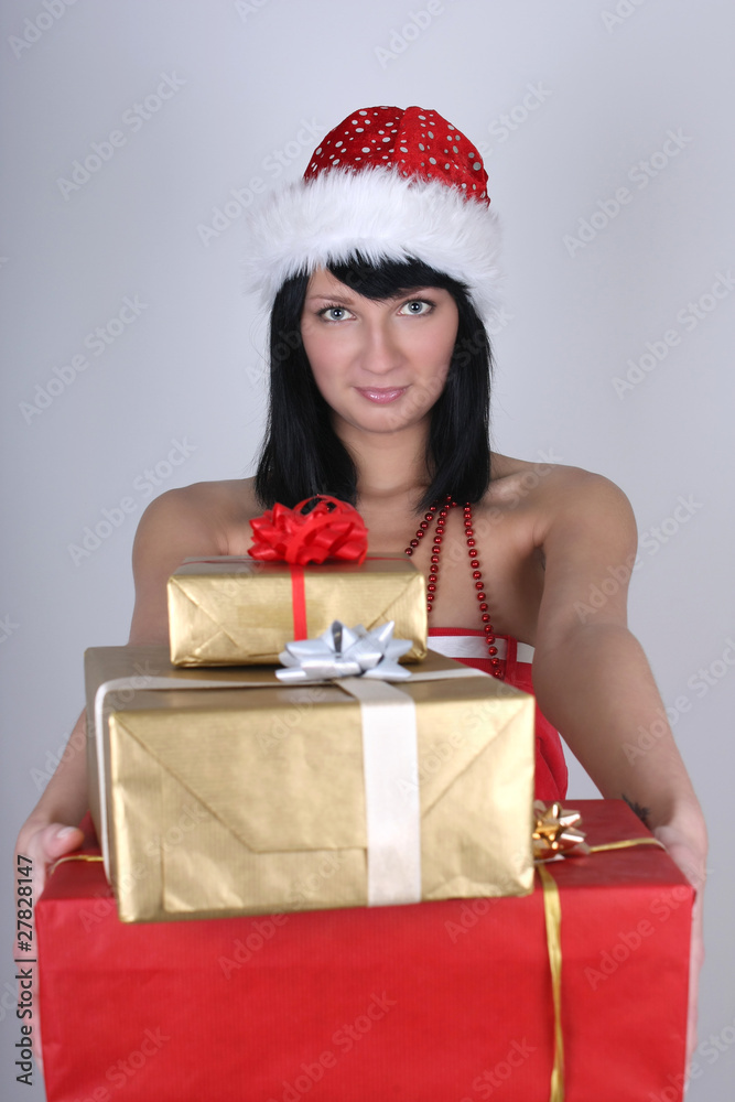 Happy brunette woman in santa hat holding golden and red present Happy brunette woman in santa hat holding golden and red present