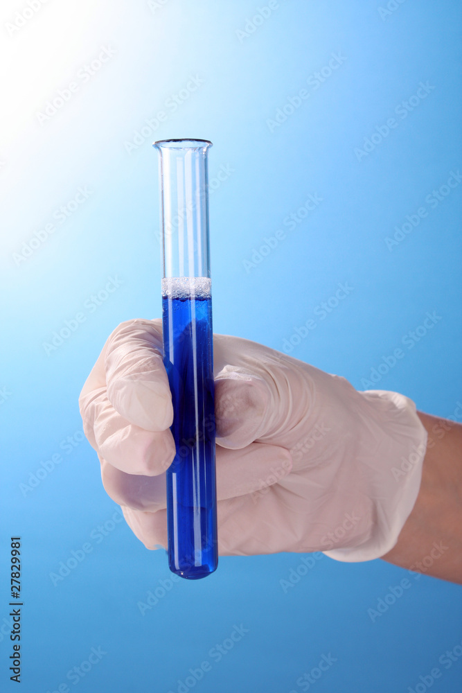 Test tube in hand over blue background Test tube in hand over blue background