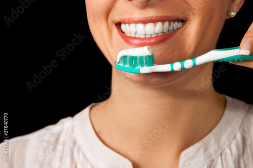Woman healthy teeth closeup with toothbrush on black background