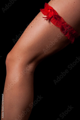 Woman leg with red scarf on black background