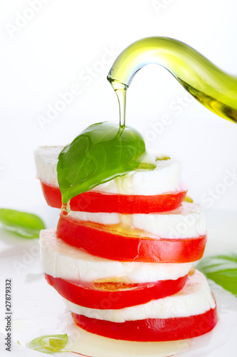 Fresh salad with mozzarella, tomato and basil with olive oil pou photo