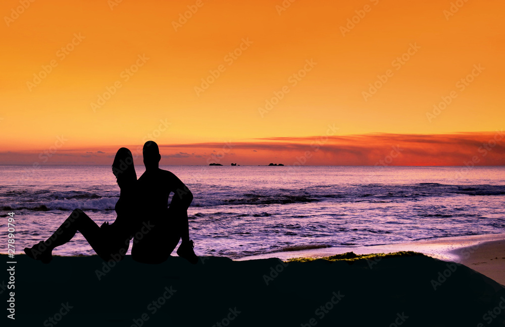 Couple sitting at the beach at sunset