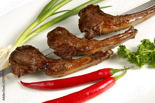 Grilled meat on bone and skewer with fresh vegetables