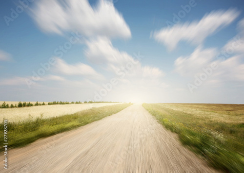 Rural motion blurred road and blue sky with summer clouds