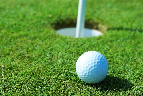 Golf ball on green grass in front of hole