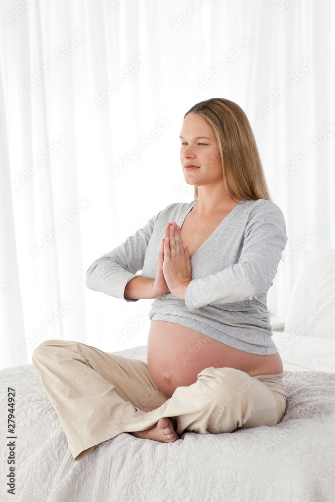 Side view of a pregnant woman doing medidation on a bed Side view of a pregnant woman doing medidation on a bed